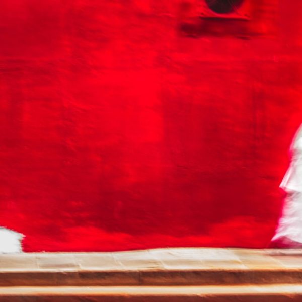 two nuns in white walking in front of red wall