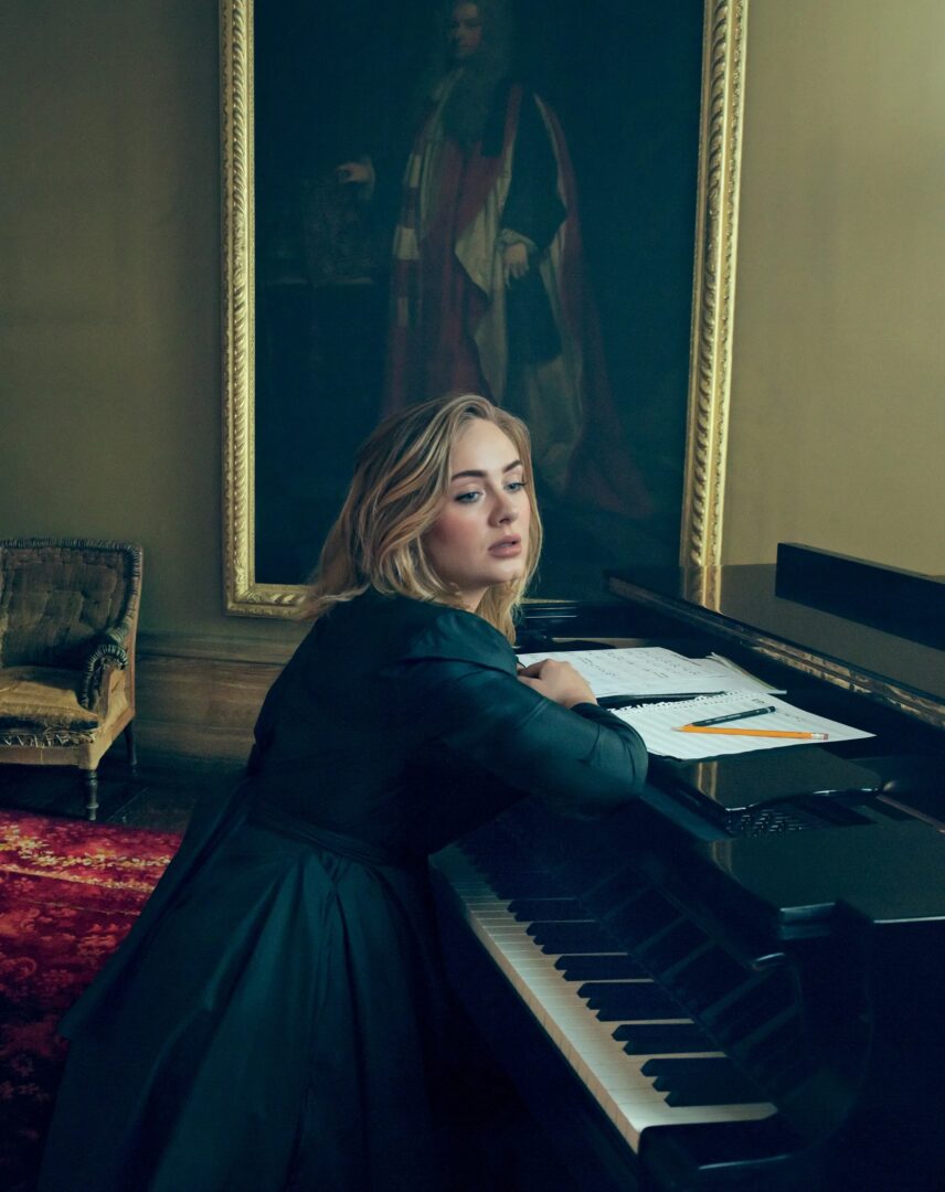 Adele reclining in a pink armchair beside a grand piano at Claridge's, Giambattista Valli dress