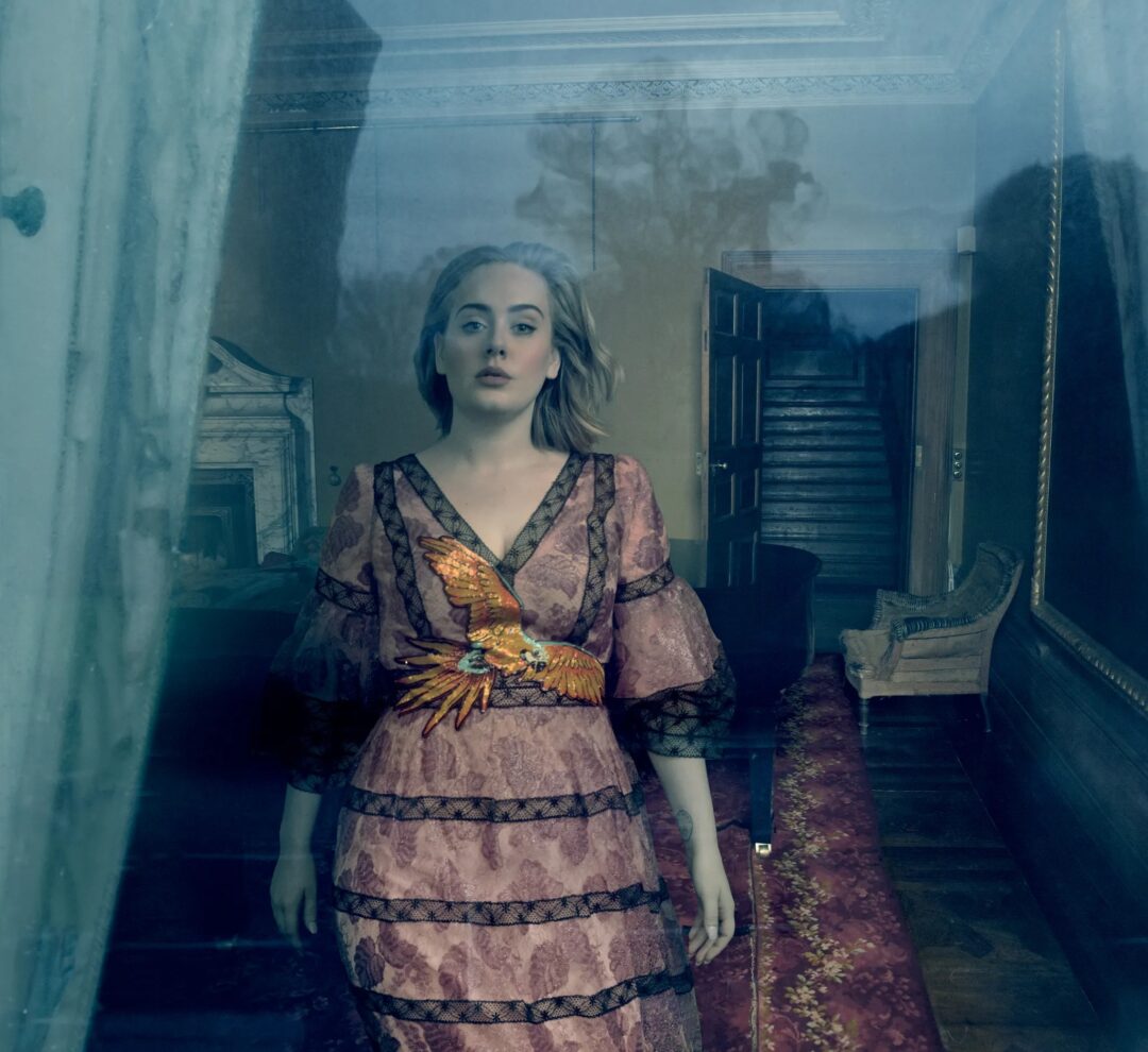 Adele photographed through reflective glass with an open doorway behind her, Gucci dress